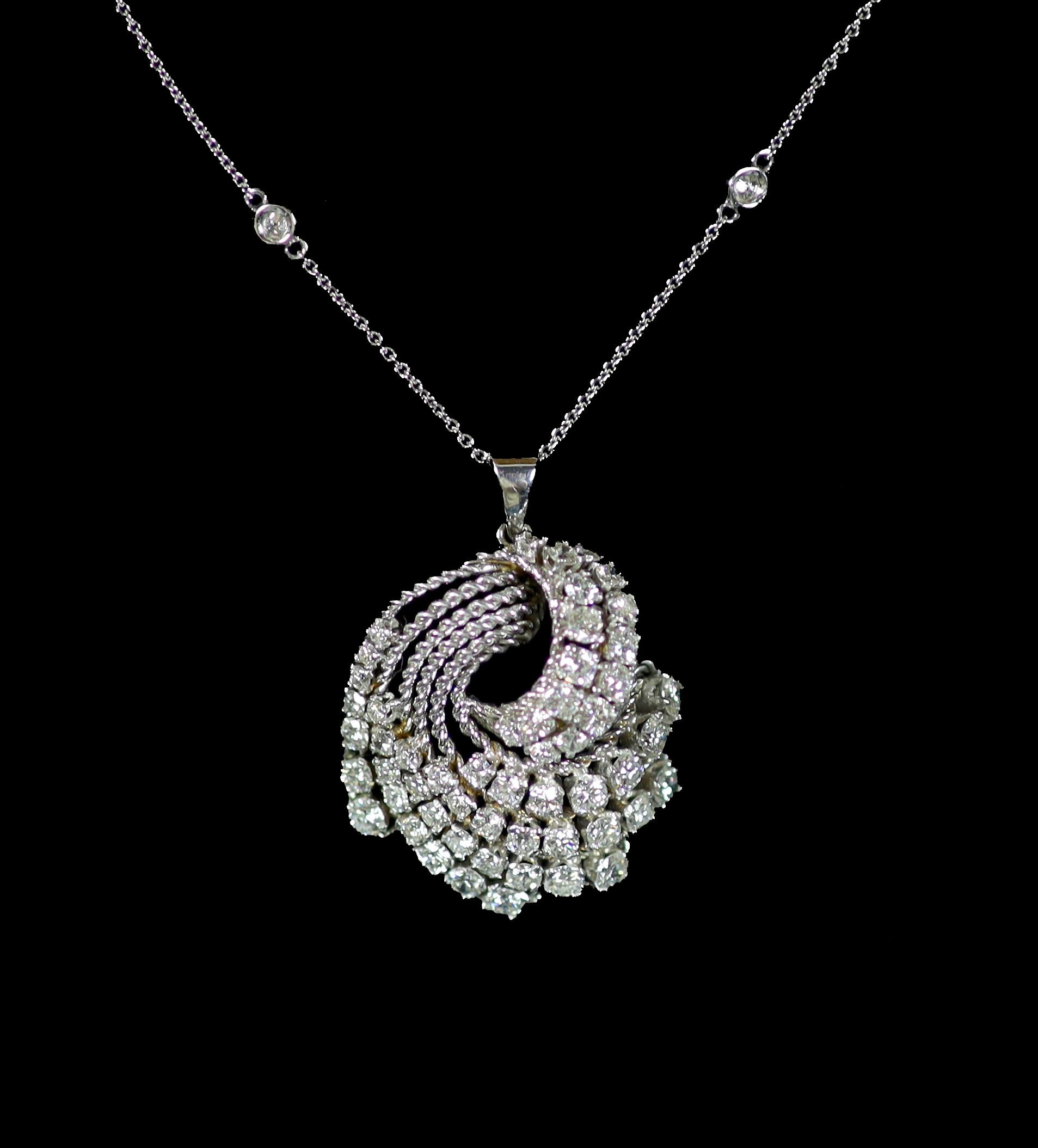 A modern white gold and graduated diamond set fan shaped scroll pendant, on a eight stone diamond set 18ct white gold chain